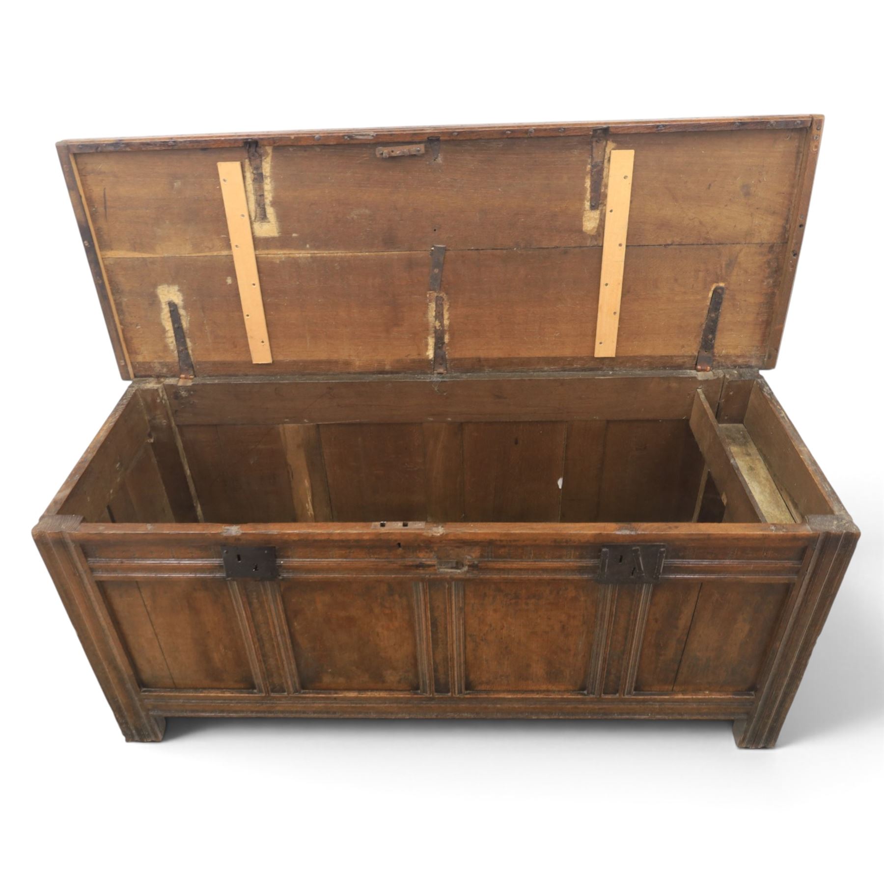 Large 17th century oak coffer, plank top with moulded edge, four panel front with channel moulded uprights, retaining original wrought iron strap hinges and central lock plate, panelled ends, raised on stile supports