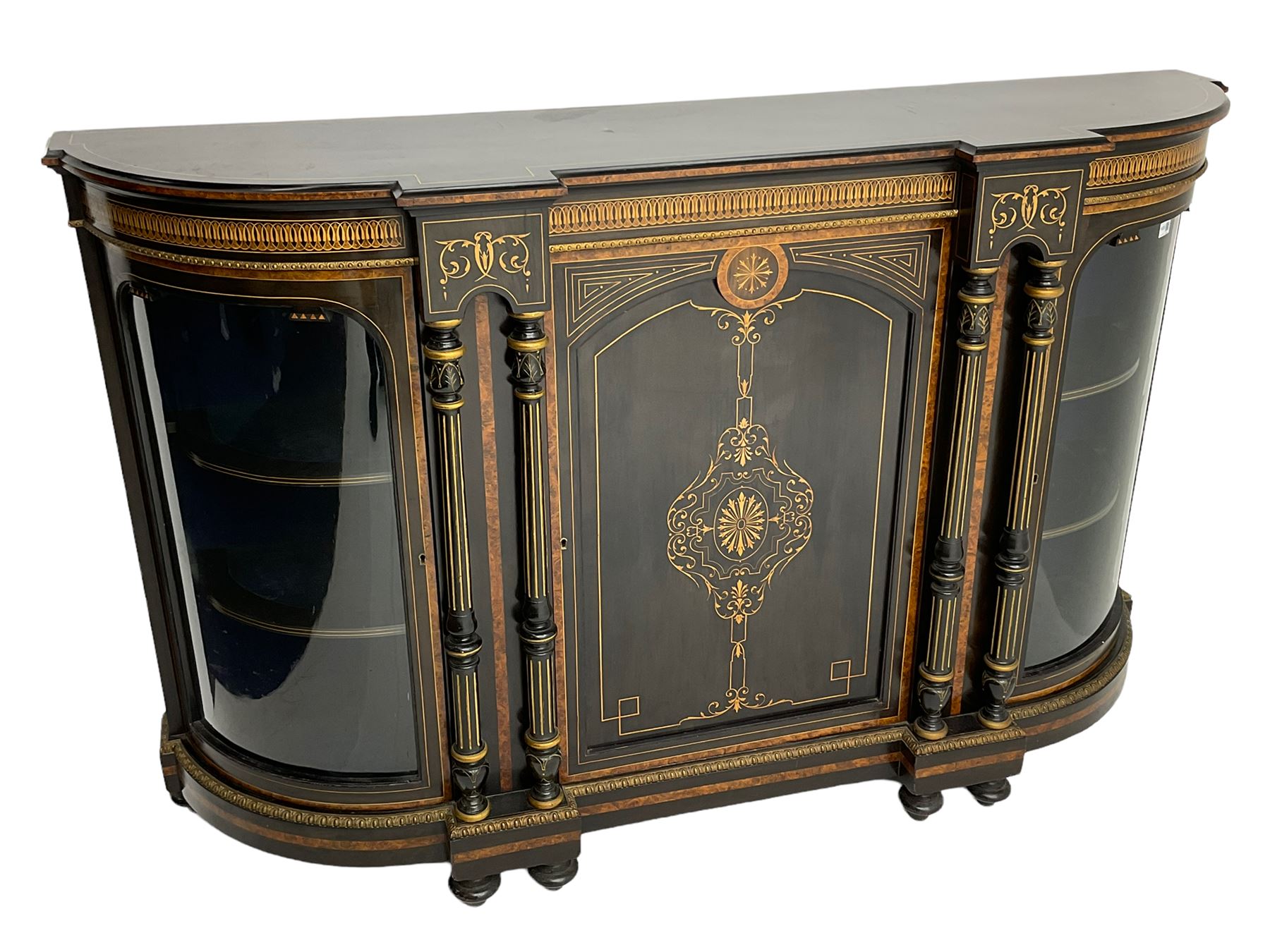 Victorian ebonised and inlaid credenza, break-front with curved ends, the front fitted with two curved glazed doors and central panelled door, inlaid with scrolling foliate and star motifs, quadruple turned and fluted pilasters to front, gilt egg and dart moulded edge on plinth base with figured walnut band, on turned feet