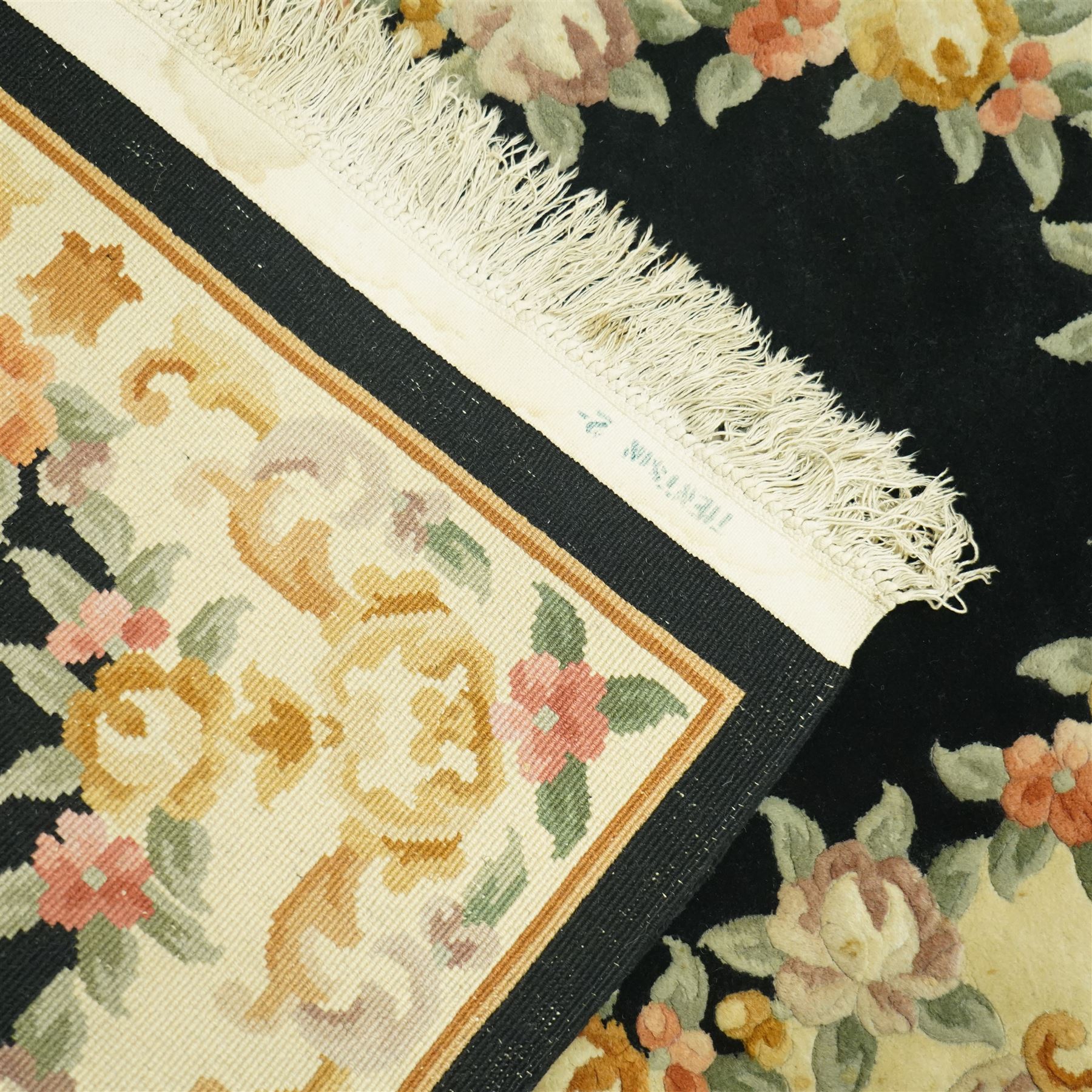 Chinese Aubusson design wool rug, black field with a central oval floral medallion framed by a wide border of scrolling flowers and foliage in soft pastel tones, with ivory spandrels and cotton fringe ends 