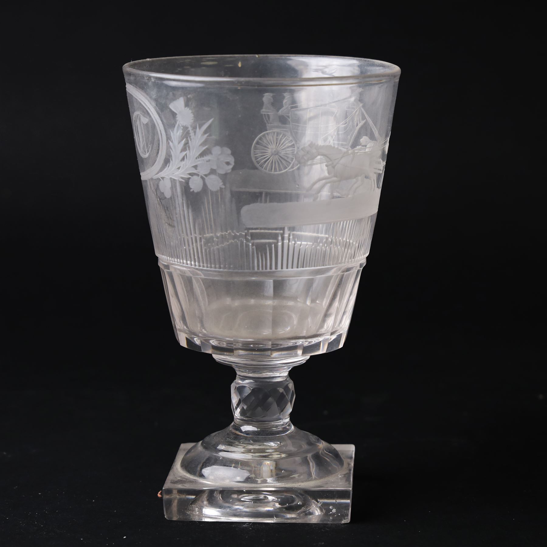 Early 19th century glass rummer, the deep bucket shaped bowl engraved with an oval roundel containing initials BC flanked by flowers of the Union, and a carriage drawn by four horses, above cut fluted and vertical cut bands, upon a short diamond cut knop stem, and square base, H15cm