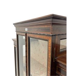 Late 19th century walnut and mahogany display cabinet, breakfront with carved dentil cornice, the friezes inlaid, fitted with four glazed doors surrounded by beading and crossbanding with further ebony inlay, three shelves fitted to the interior, raised on square tapering supports with spade feet
