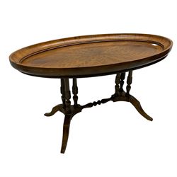 Early 20th century walnut coffee table, oval dished top with sunburst matched veneer, raised on twin cluster columns united by turned stretcher base on splayed supports