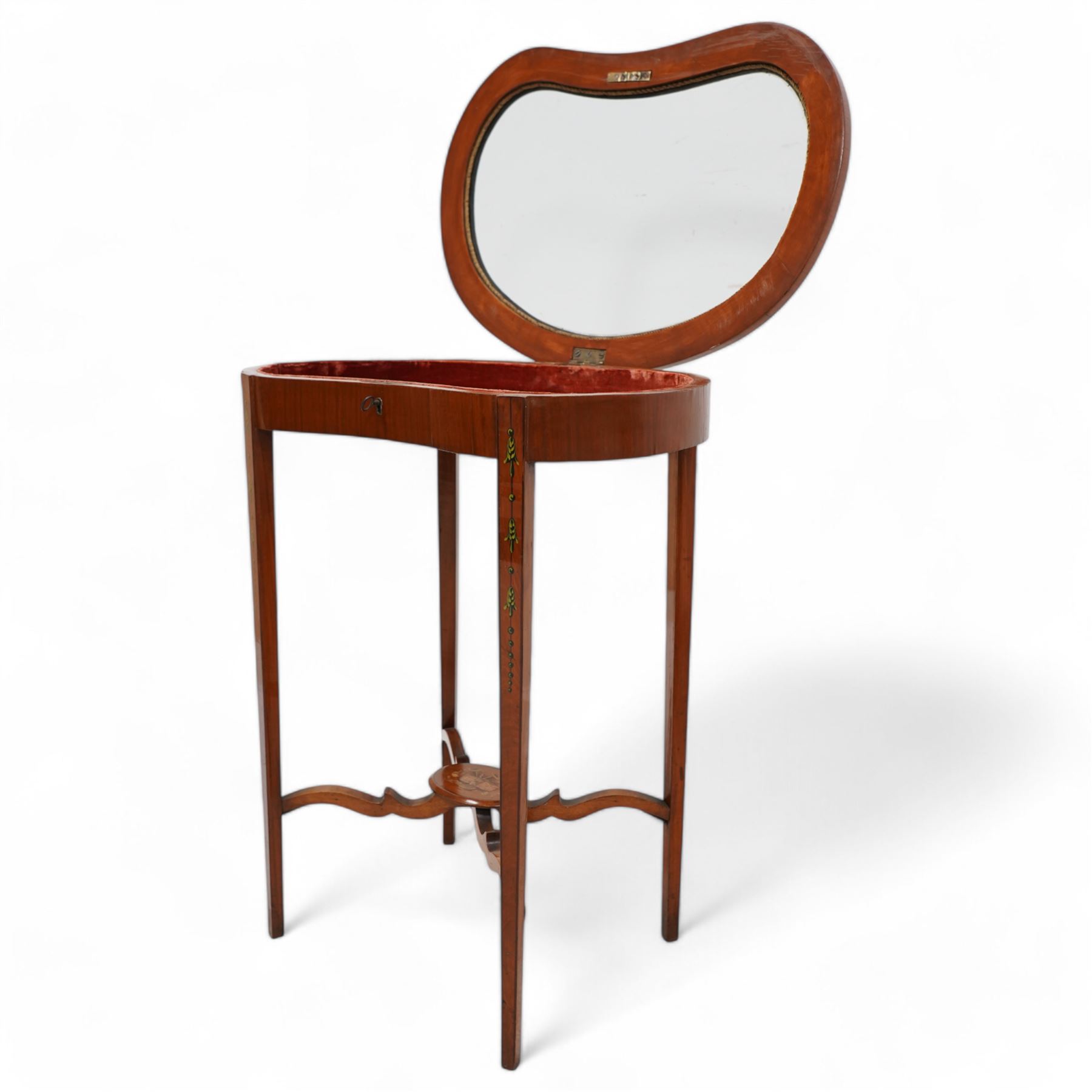 Edwardian satinwood kidney-shaped bijouterie table, hinged lid with glazed panel enclosed by floral painted frame, on square tapering supports decorated with trailing bell flowers, united by shaped stretchers and oval tier painted with ribbon and trumpets 