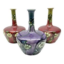 Three Minton Secessionist vases, with tube-lined stylised flower decoration, two upon a red ground and third upon a purple ground, all with printed mark to base 'Minton Ltd, No. 33', H13cm