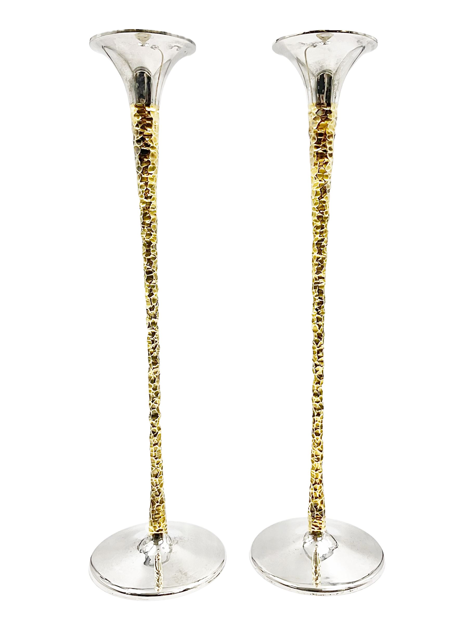 Pair of modern silver candlesticks by Stuart Devlin, the tapering parcel gilt stems with signature textured detailing, each supporting a fluted candle holder and upon a spreading circular foot, hallmarked Stuart Devlin, London 1973, H25cm