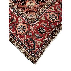 Persian Heriz dark indigo and red ground carpet, the central medallion with large projecting palmette motifs, overall floral design decorated with stylised plant motifs, repeating patterned border within guard stripes