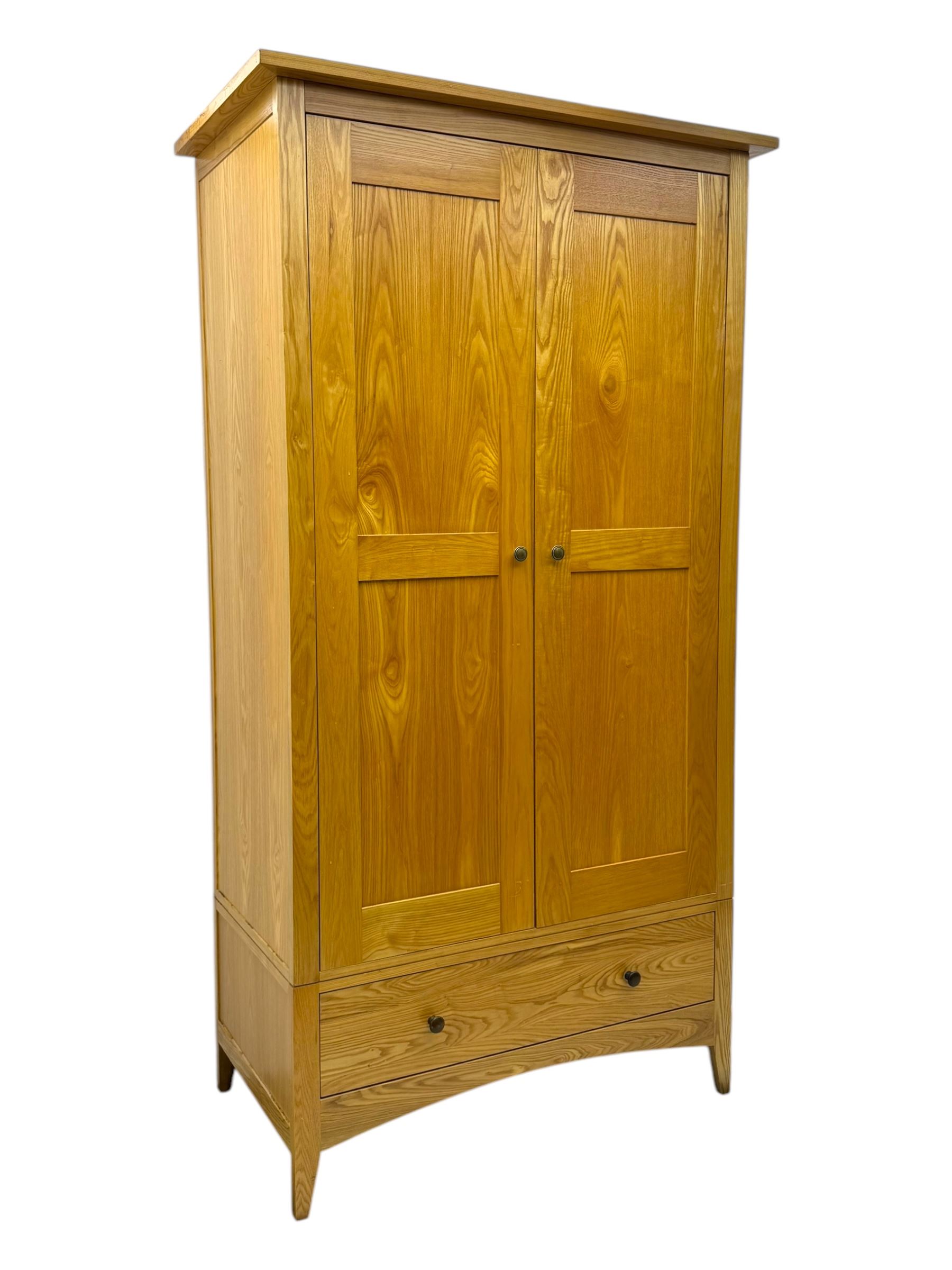 Contemporary light oak double wardrobe, projecting cornice over two panelled doors enclosing hanging rail and shelf, above full-width drawer, on shaped stile supports