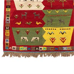 South West Persian Qashqai kilim, the field arranged with stepped polychrome panels depicting stylised camels, goats, cattle and birds, interspersed with trees and flowering stems, enclosed by a red border with multicoloured geometric devices
