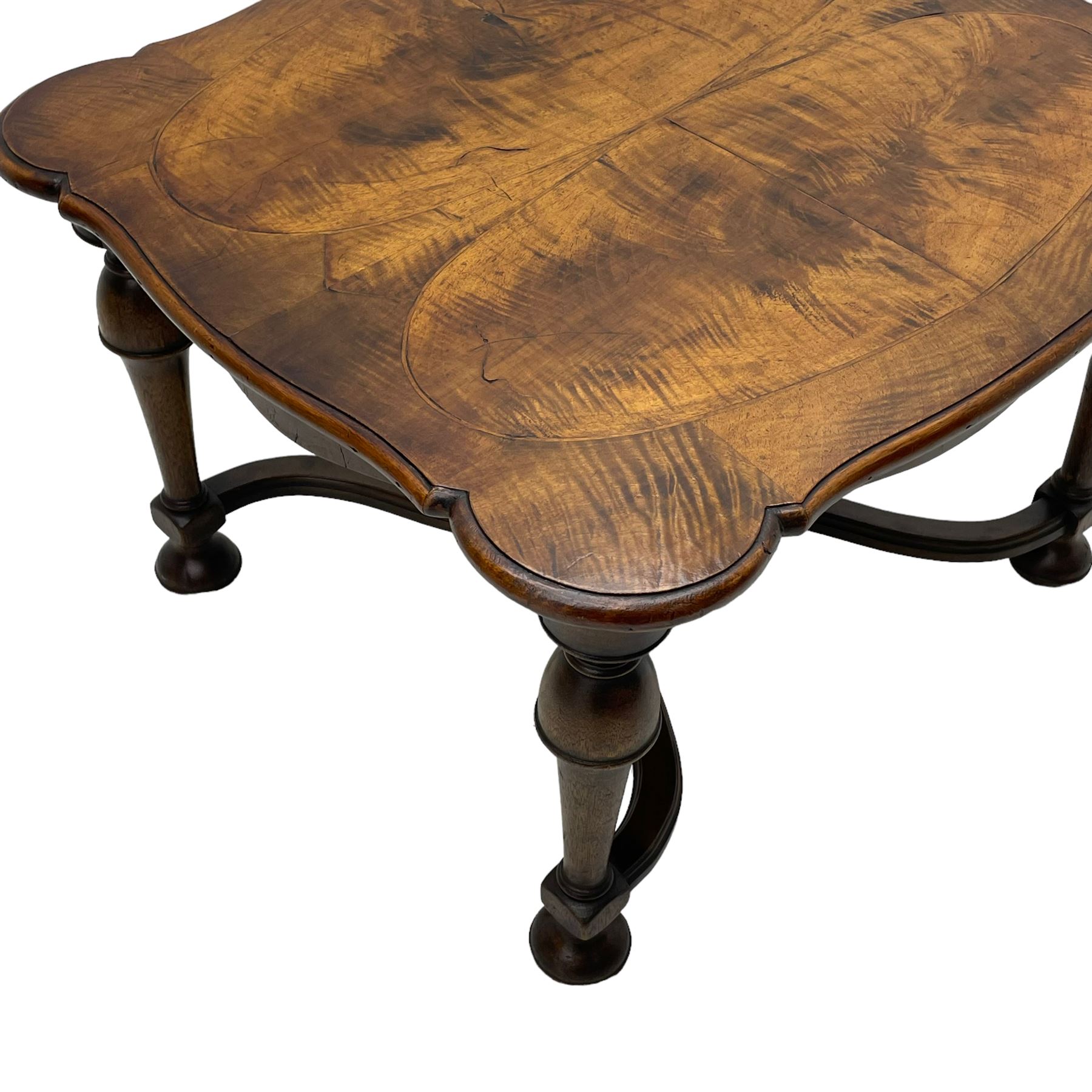 Figured mahogany coffee table, shaped moulded top with oval book-matched veneered panels, on turned supports united by waved X-shaped stretchers 