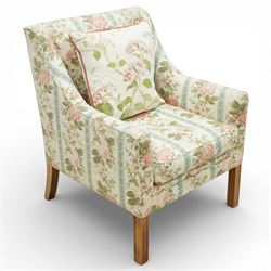 Pair of Edwardian upholstered armchairs, each with shaped padded back flanked by scroll arms, loose seat cushions, upholstered throughout in rose patterned fabric with vertical floral bands, raised on square tapering wooden legs