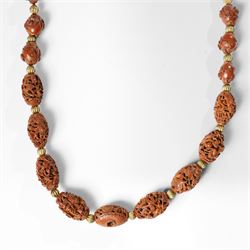 Chinese Hediao necklace, comprising twenty-one pierced and carved seeds strung with smaller beads, the carvings depicting birds among foliage, crabs and fish, figures and warriors, and other traditional scenes, length 82cm 
