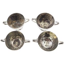Set of four Edwardian silver open salts and salt spoons, the open salts of circular form with twin curved handles, upon a spreading circular foot, with later blue glass liners, hallmarked Wakely & Wheeler, London 1901, contained within a shaped fitted case with green silk and velvet lined interior, approximate total silver weight 8.64 ozt (268.9 grams)
