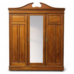 Edwardian walnut triple wardrobe, shaped broken-arch pediment over three doors comprising ...