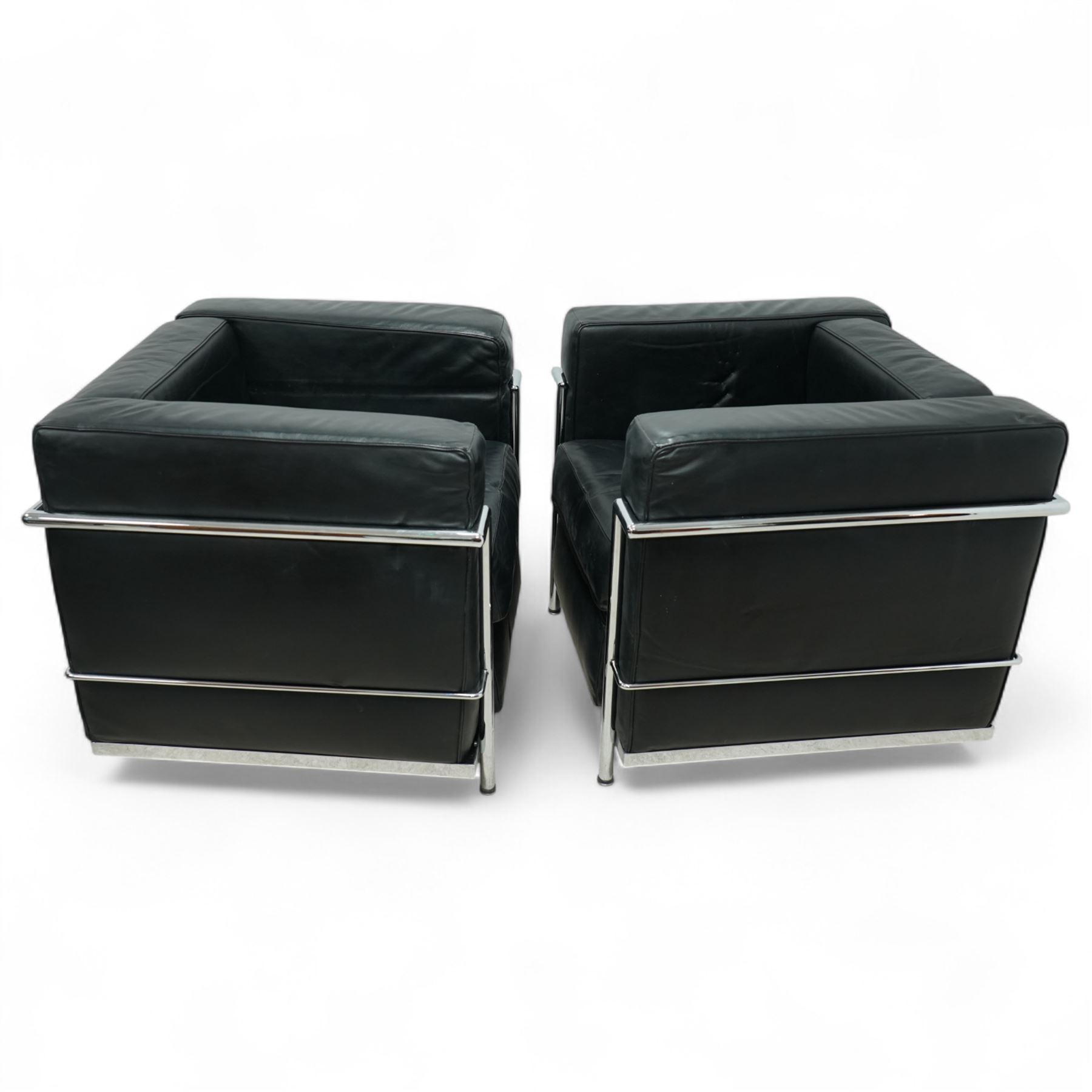 Contemporary pair of black leather chrome arm chairs of Le Corbusier LC2 inspired design, cube form with loose seat and back cushions enclosed in a tubular chrome frame and supports