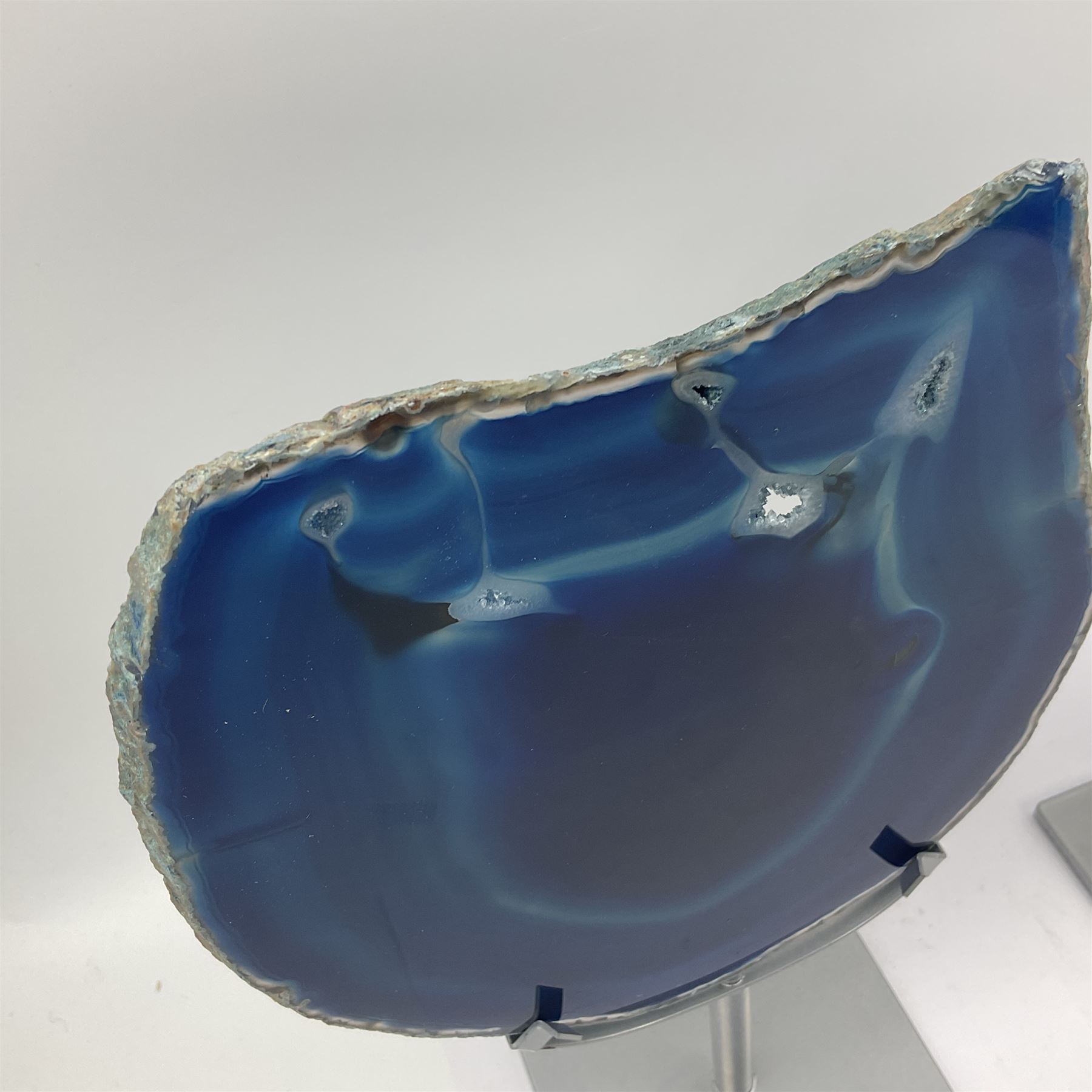 Pair of blue agate slices, polished with rough edges, raised upon silvered metal stands, H26cm