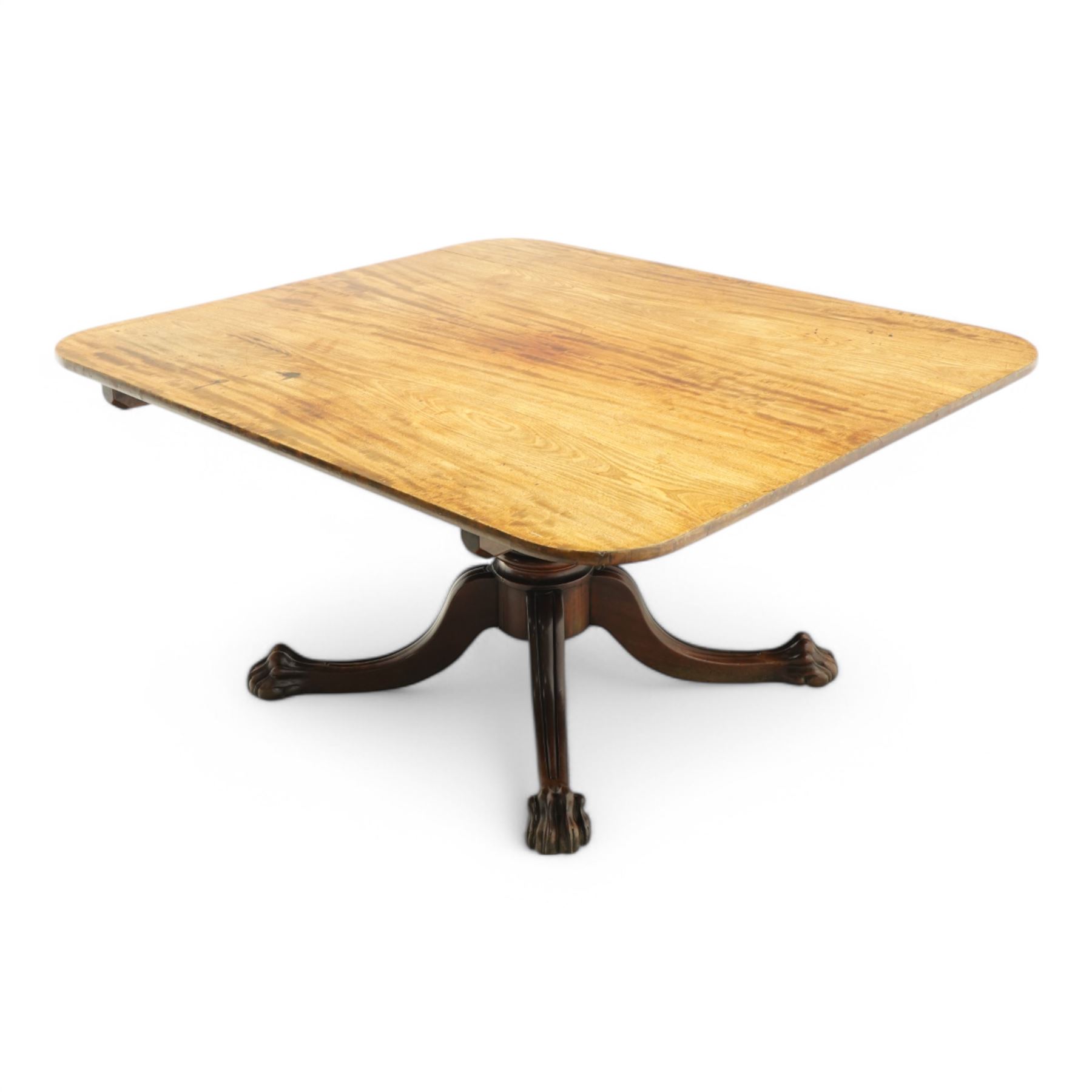 Large Regency mahogany breakfast table, figured rectangular tilt-top with rounded corners, on wide turned pedestal with four out-splayed moulded supports, paw carved terminals with recessed castors 
