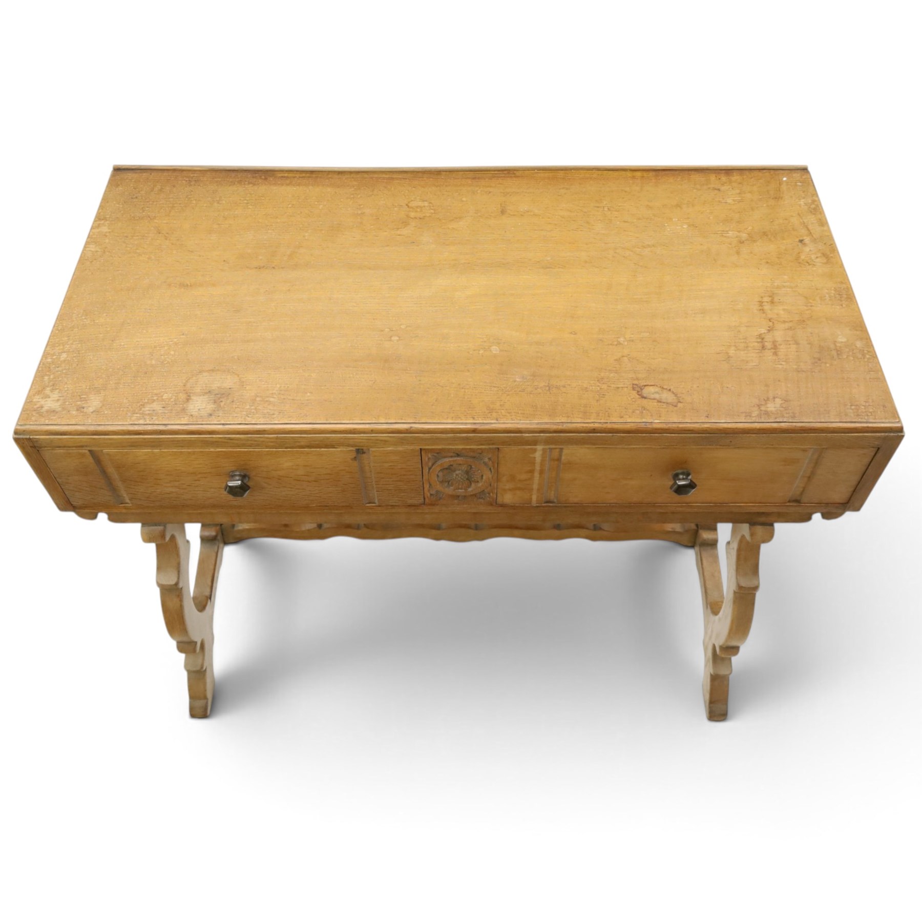 Leemings of Halifax (est. 1872) - Arts & Crafts oak side table, rectangular caddy top with raised moulded back, the frieze carved with central Yorkshire rose motif flanked by two drawers, raised on twin stylised lyre end supports formed of C-scrolls, united by shaped stretcher