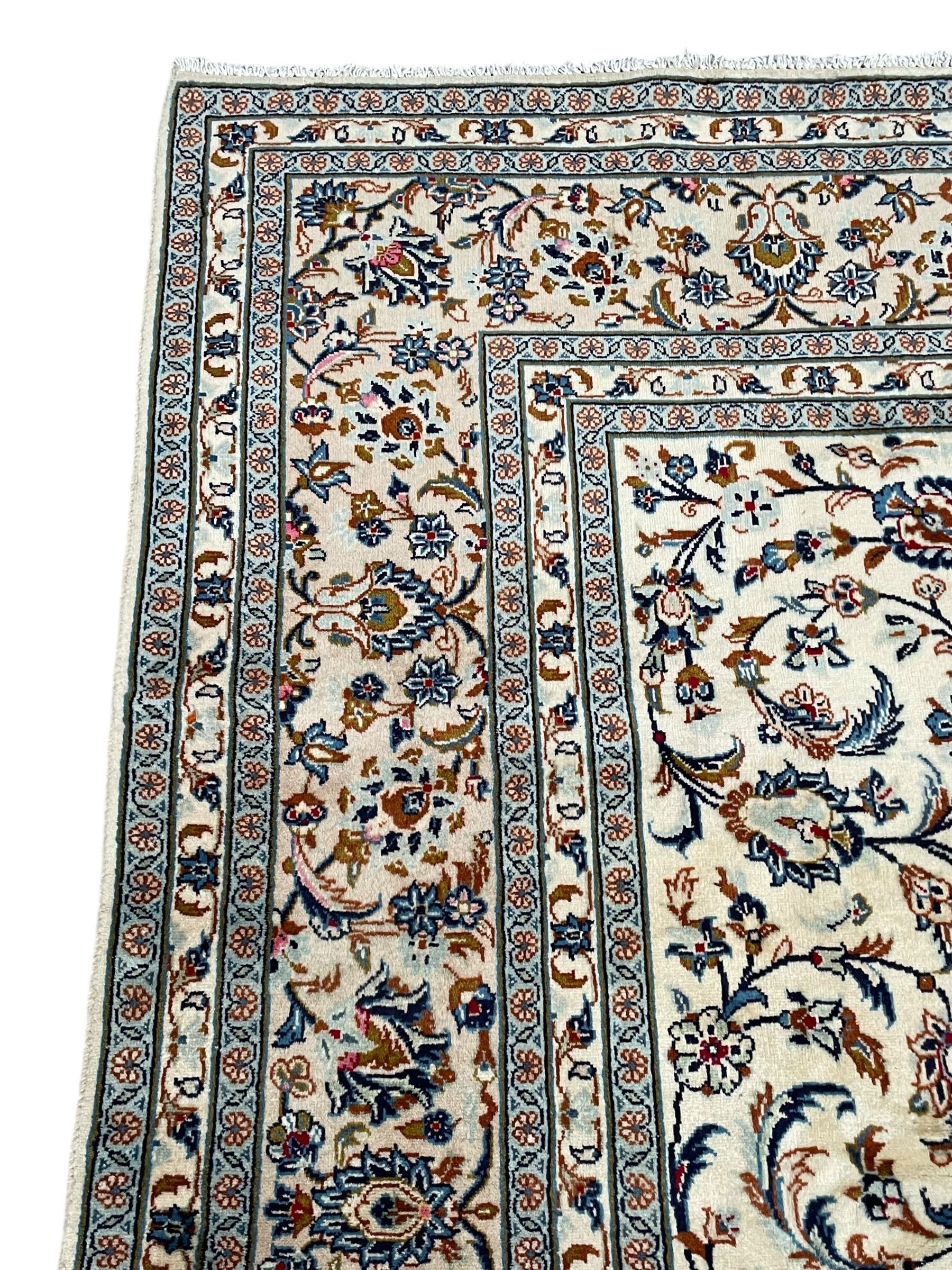 Persian Kashan ivory ground rug, decorated with curled leafy branches and palmettes, the border with scrolling design decorated with further palmettes, within floral pattern guard stripes