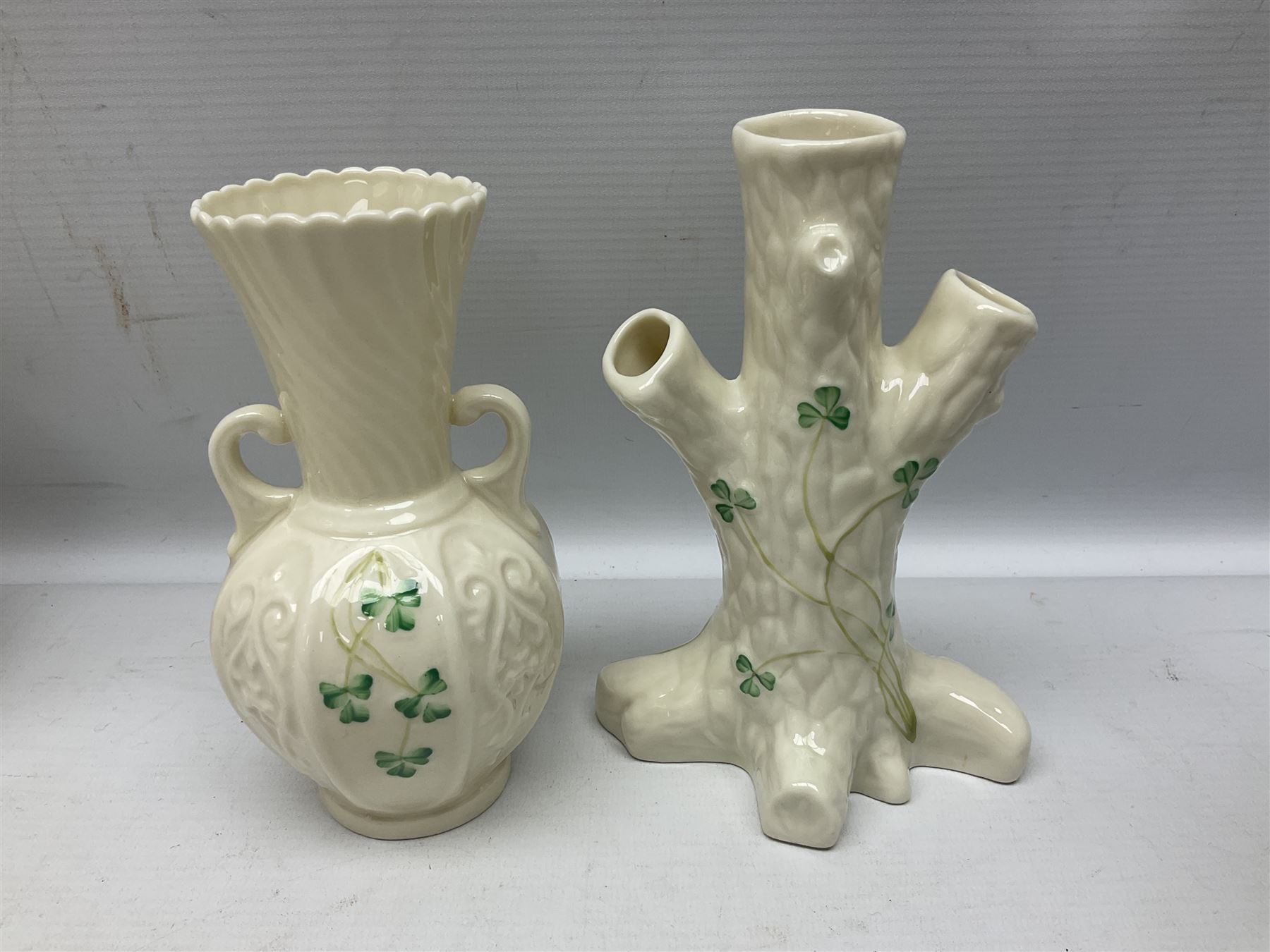 Five late 19th/early 20th century and later Belleek vases, comprising pair of Lotus Blossom examples, shamrock tree trunk vase, twin handled shamrock vase and a baluster form vase decorated with applied roses, all with printed marks beneath, tallest H16cm