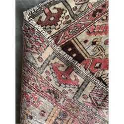 Persian Heriz red and pale ground rug, depicting multiple shaped panels with stylised motifs and designs, geometric patterned border