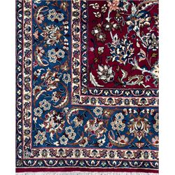 Central Persian Yazd hand-knotted rug, madder red field with scrolling vines, palmettes, and rosettes around a cusped lozenge medallion within a blue ground border of palmettes and flowerheads, 366cm x 250cm