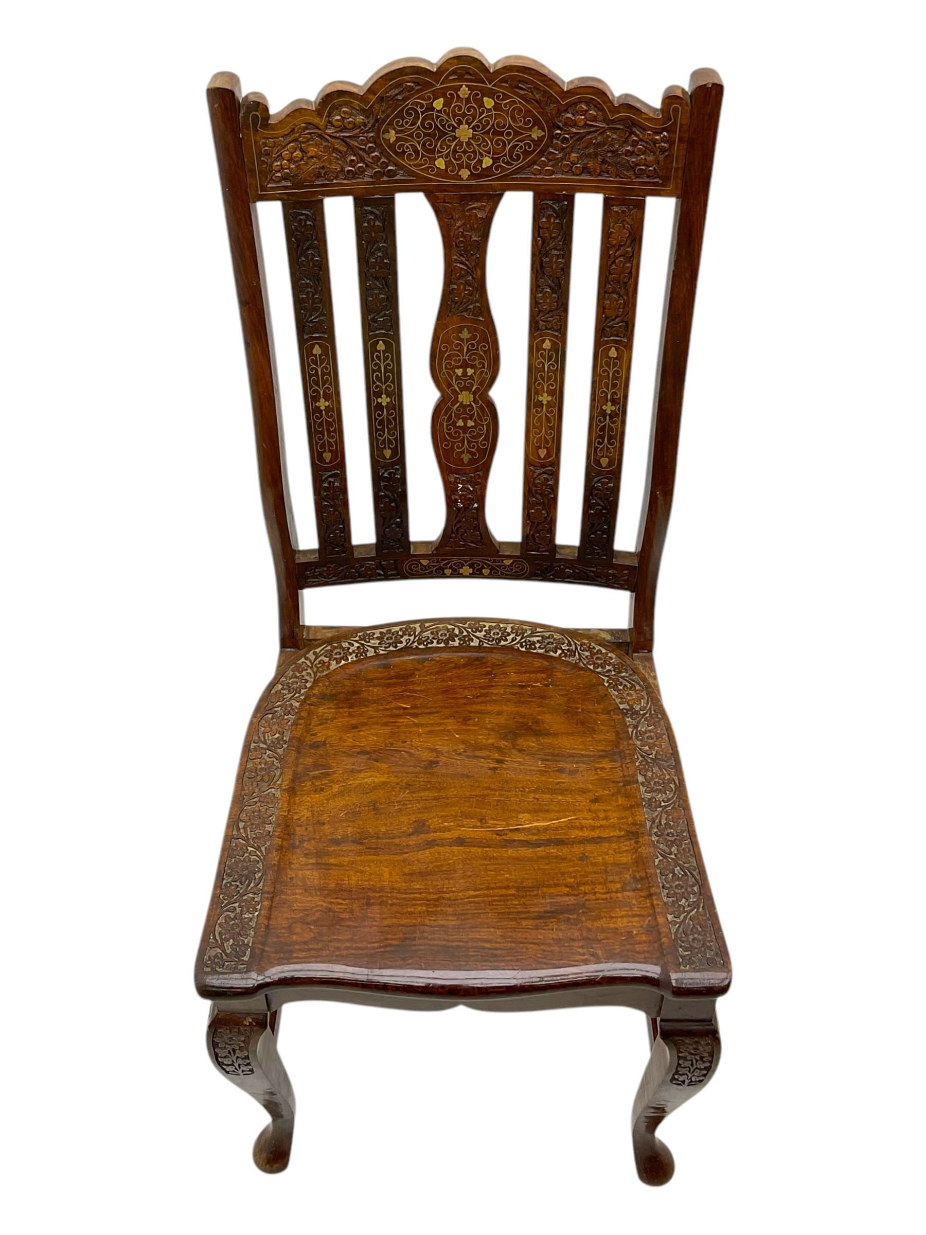 Pakistan carved hardwood brass inlaid circular dining table, and four rail back chairs with saddle seats