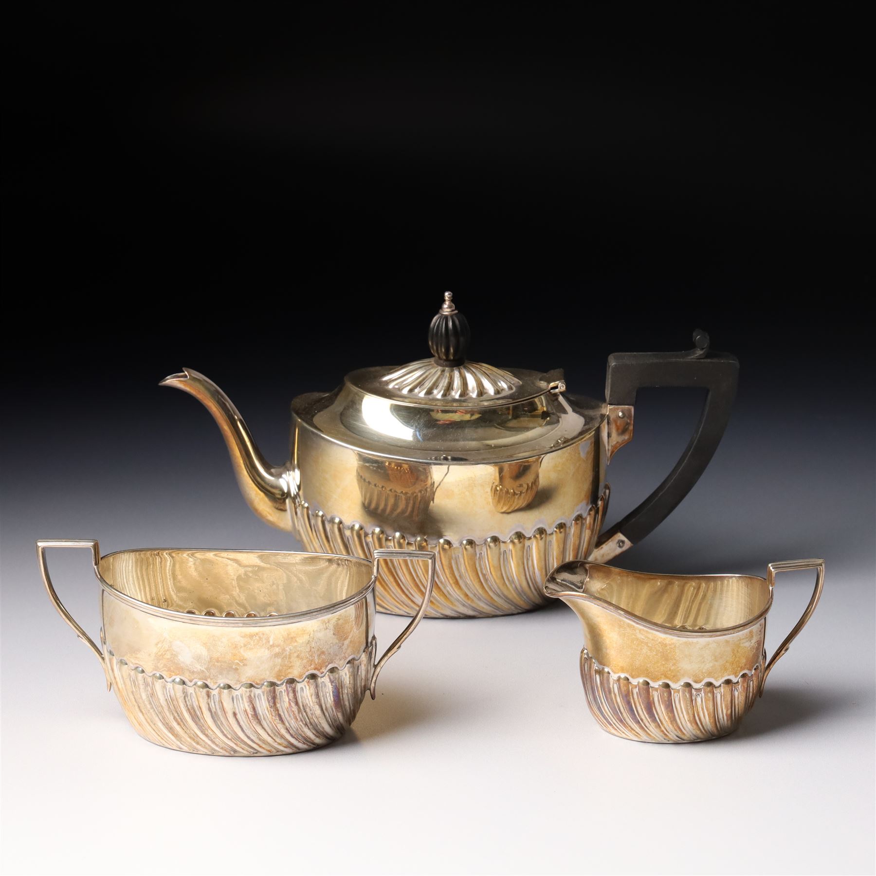 Late Victorian bachelors silver tea set of oval form with half body decoration, the teapot with ebonised handle and lift Sheffield 1895 Maker Harrison Bros. & Howson