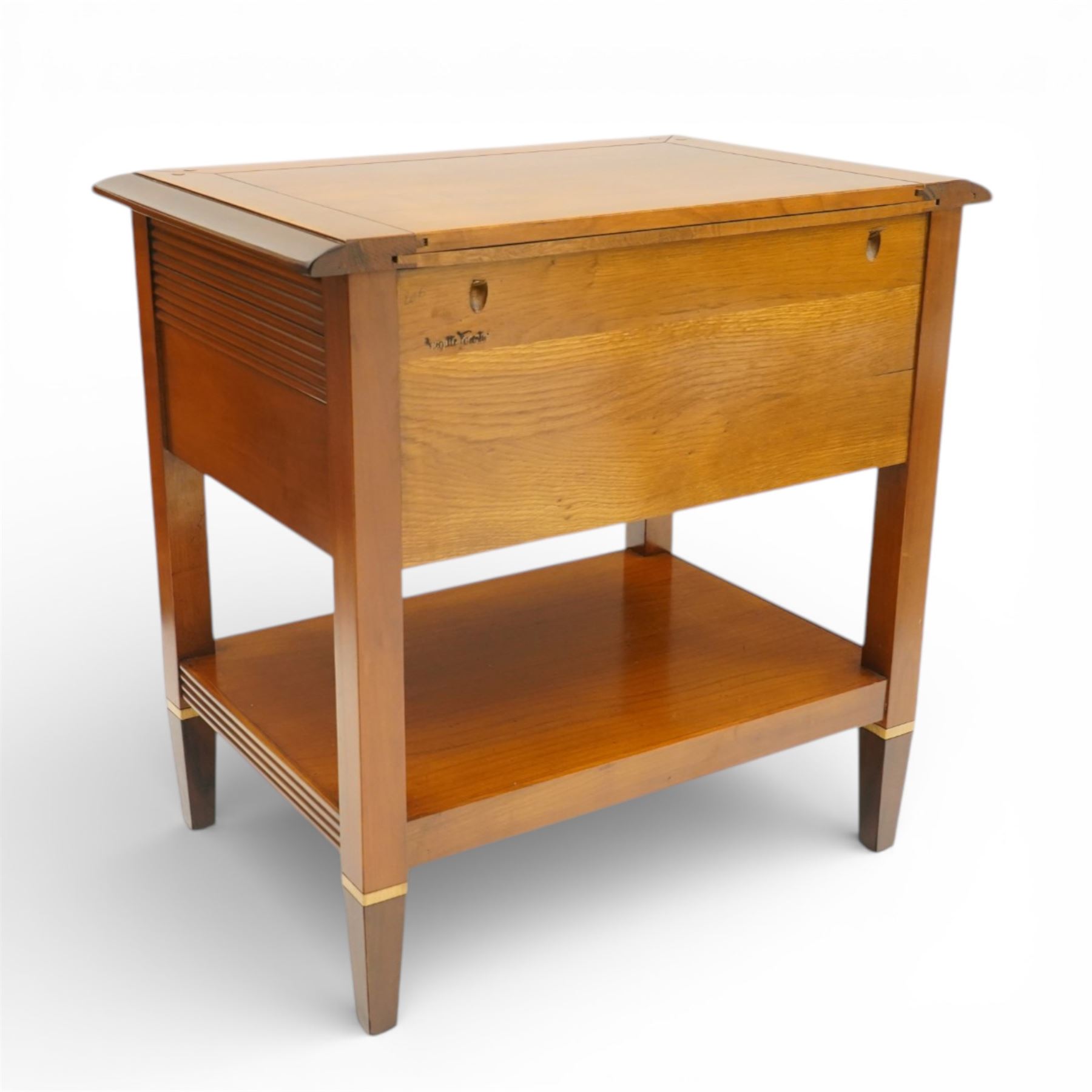 Brigitte Forestier - pair of cherry wood bedside cabinets, moulded rectangular top above two drawers, the top drawer with reeded panels flanking a brass circular pull, the lower drawer with two brass pulls, on square tapering supports united by a full length undertier