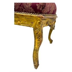Pair of Louis XV-design giltwood stools, each upholstered in red damask fabric with slight variations in patterns, the carved frames adorned with scrolling foliage and shell motifs, raised on cabriole supports