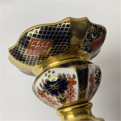 Pair of modern Royal Crown Derby Old Imari 1128 pattern candlesticks, each with shaped drip tray affixed to squat socket, upon spreading stem and canted square base with gilt dolphin edges, with printed marks beneath including Roman numeral year cypher for 2003, H26.5cm, with original boxes