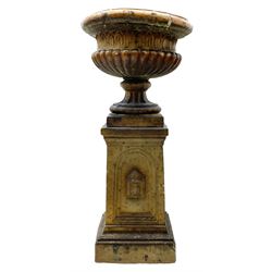 Victorian salt glazed terracotta garden urn on plinth, the Campana shaped urn with foliate decoration over gadrooned underbelly, the plinth of square tapering form, each side with recessed moulded archway decorated with urn cartouches, stepped and moulded skirt base