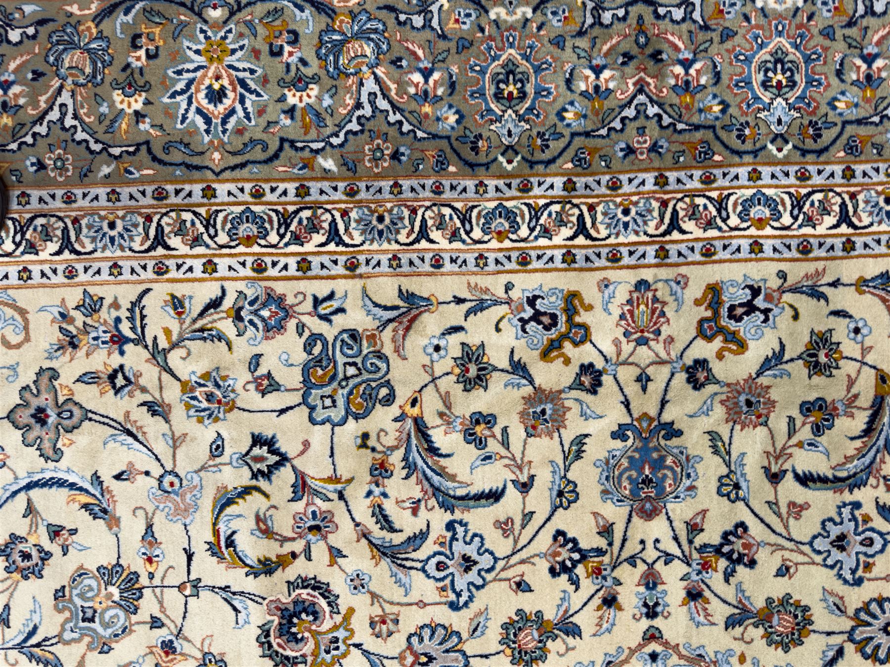 Central Persian Kashan hand-knotted carpet, ivory field with scrolling vines, palmettes, and rosettes around a cusped medallion with pendants and spandrels within a blue ground border of palmettes and flowerheads, 388cm x 300cm