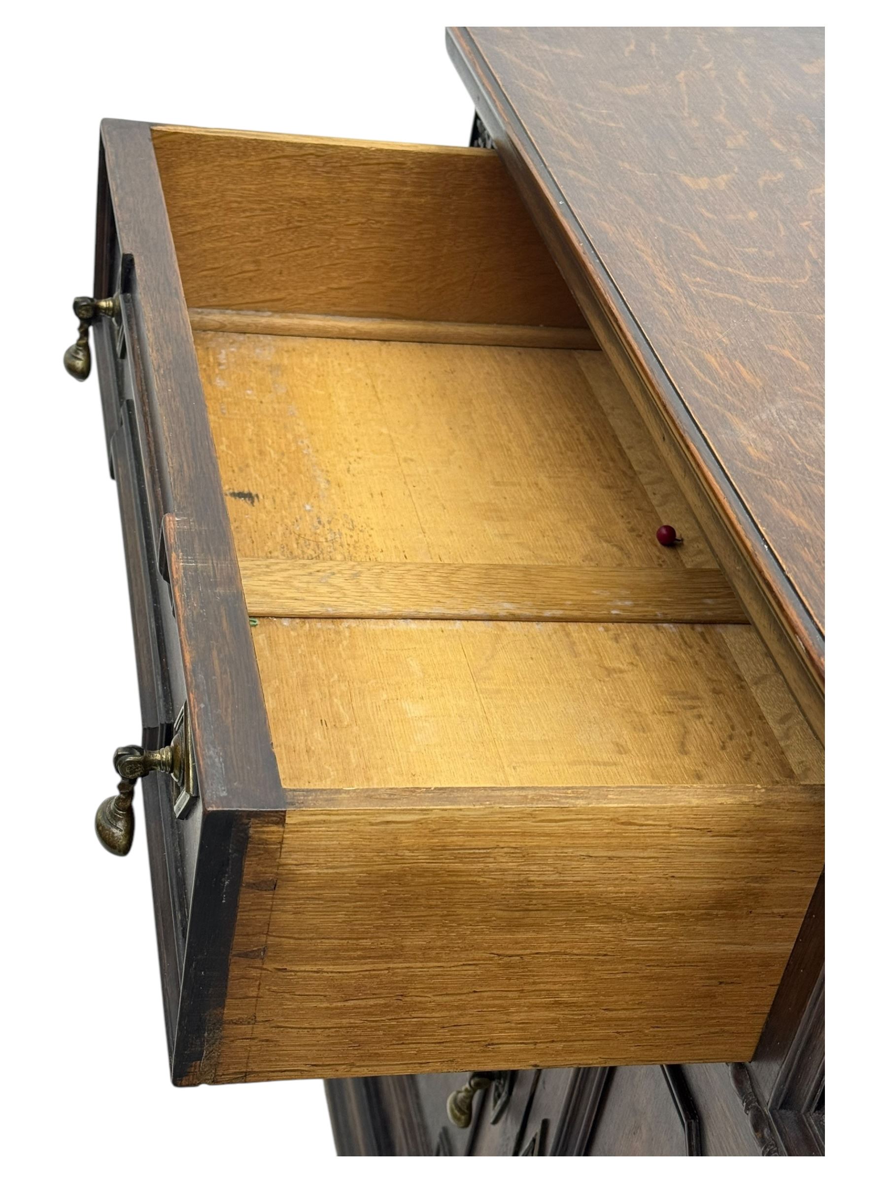 Jacobean-style oak dresser base with two frieze drawers above three cupboards with panelled and moulded decoration, fitted with drop handles, supported on bun feet, circa 1900