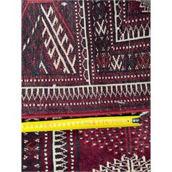 Northeastern Persian Yamut  hand-knotted carpet, the rich burgundy field with repeating rows of stepped gul motifs in cream and black, enclosed by multiple linear and geometric borders with hooked motifs and diamond medallions