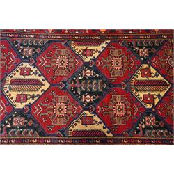 North West Persian Heriz hand-knotted rug, madder red field with an all-over lattice of stepped lozenge medallions enclosing stylized geometric floral motifs and ivory reserve panels, framed by angular vinery and motif borders, main border with with stylized rosettes and geometric devices, flanked by narrow guard stripes,, cotton fringe ends 