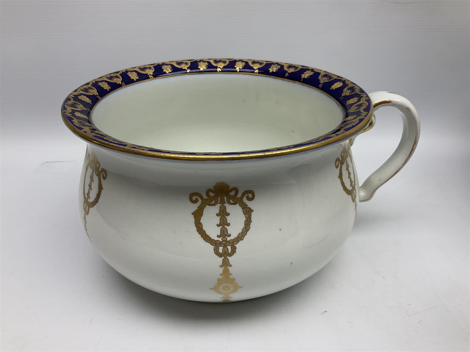 Early 20th century Bishop and Stonier four piece toilet set, comprising washbowl, wash jug, toothbrush pot, and chamber pot, each  decorated with deep blue band and husk swags and festoons in gilt, with printed Caduceus Bisto marks beneath and printed retailers mark 'Manufactured for Harrods Limited London', wash bowl D43cm, wash jug H31.5cm