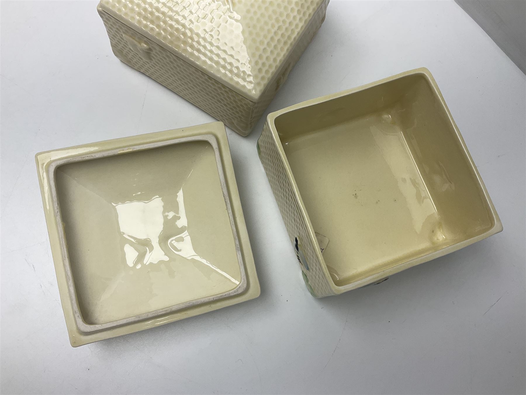 Four square honey boxes with lids,  each decorated with honeycomb pattern and finished with a bee finial