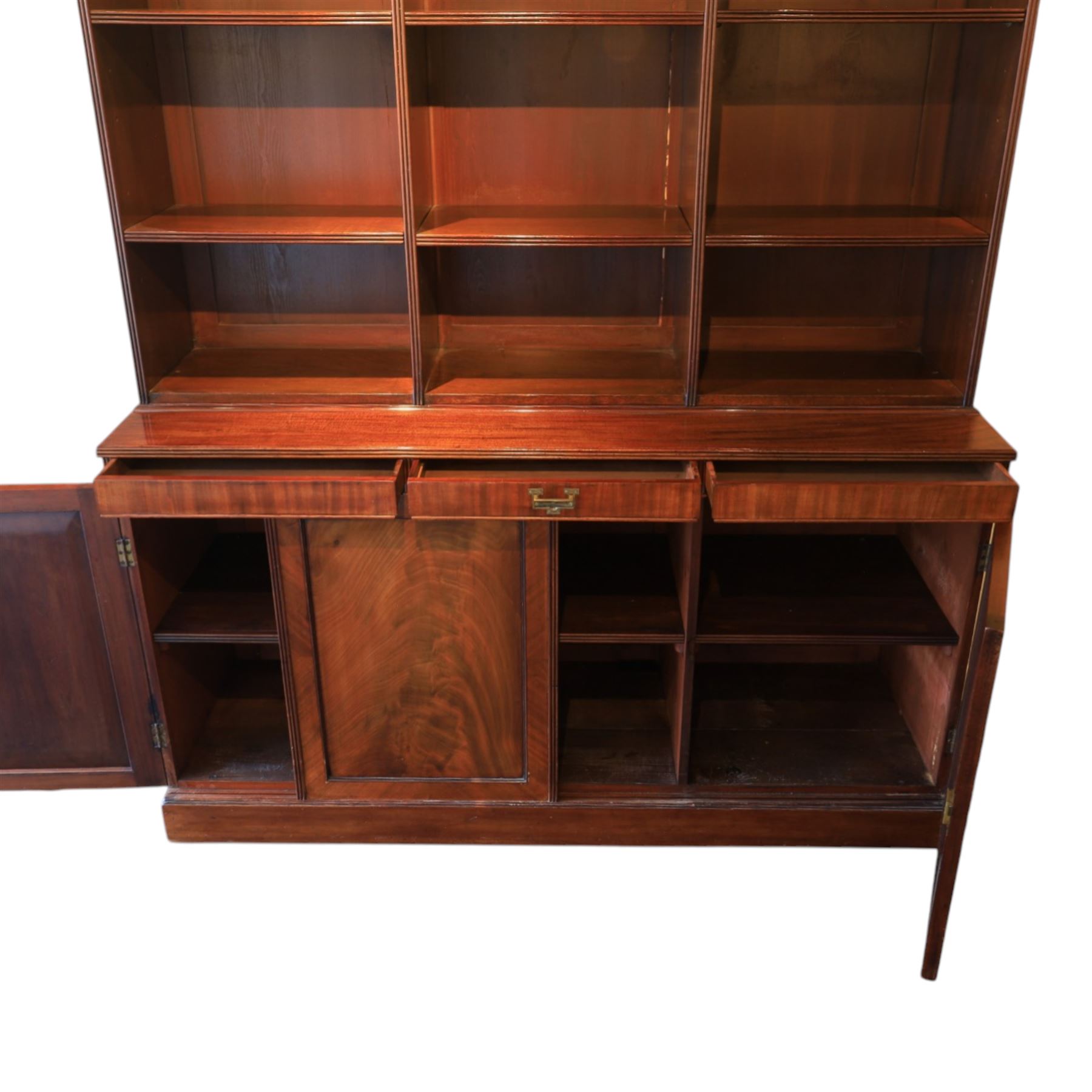 Early 20th century mahogany open bookcase, with reeded upright divisions and adjustable shelves, over a cupboard base fitted with three frieze drawers and three panelled doors, on plinth base