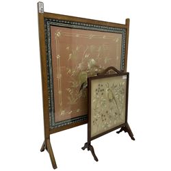 20th century oak framed fire screen, silk needle work panel depicting peacock within a naturalistic landscape with trees and flowers (W89cm, H118cm); together with a smaller fire screen (W52cm)
