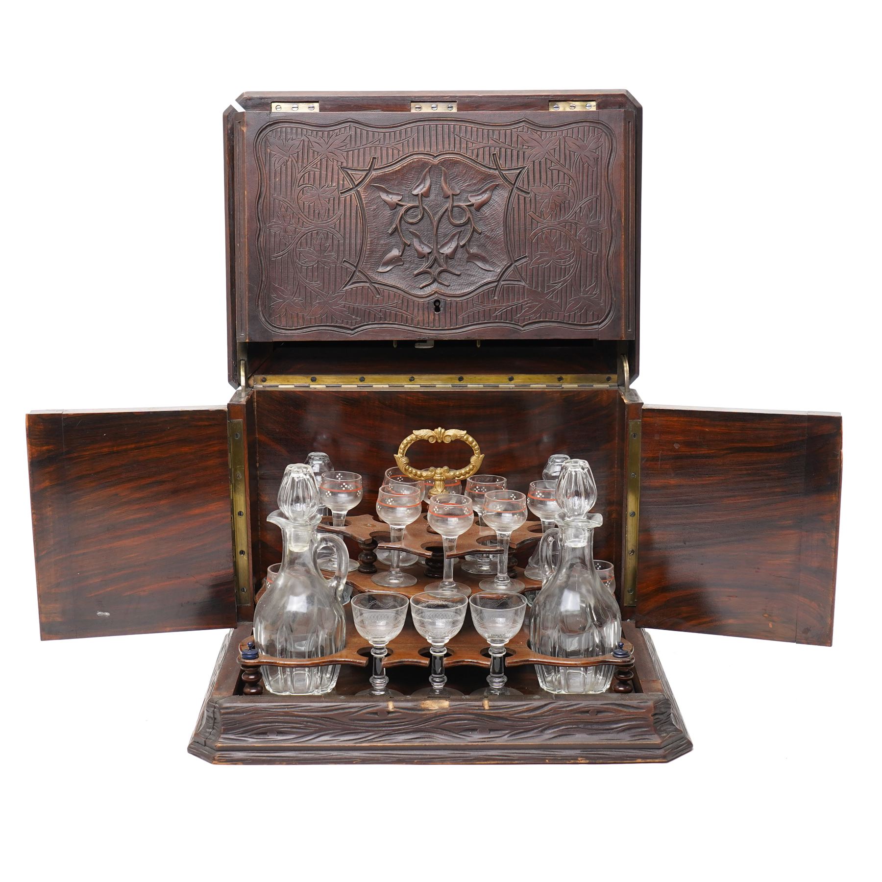 Late 19th century cave à liqueur black forest style decanter box, with carved naturalistic decoration, lifting top and fold out side panels, the interior fitted with four decanters and sixteen glasses, the smaller glasses with applied painted decoration, the others with etched design, with key, when closed overall W36cm x D29cm x H28cm 