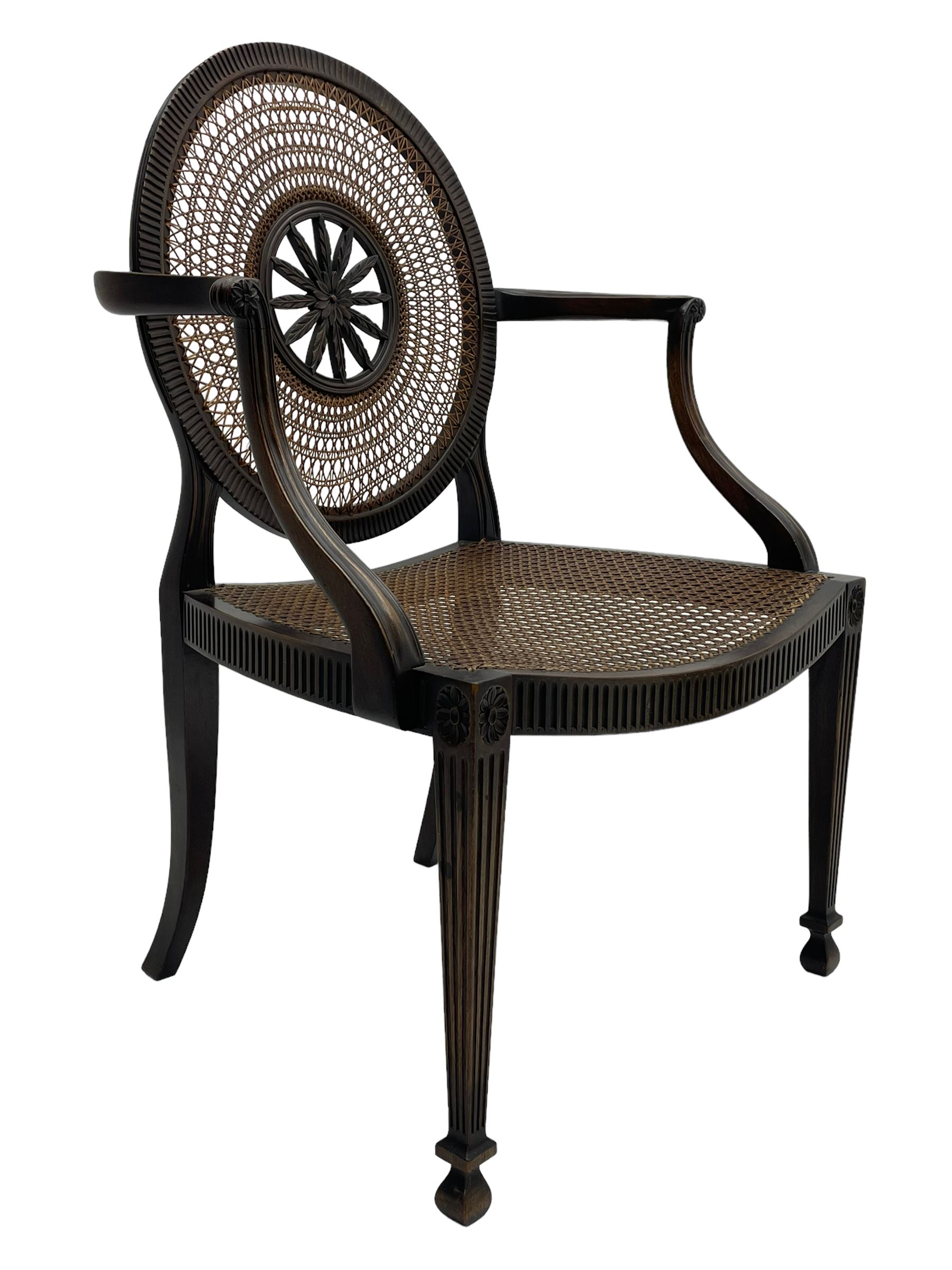 Mid-to late 20th century walnut Hepplewhite design elbow chair, circular cane back with pierced and carved central rosette, fluted frame with scrolling arms, cane seat raised on fluted rail and square tapering supports with spade feet