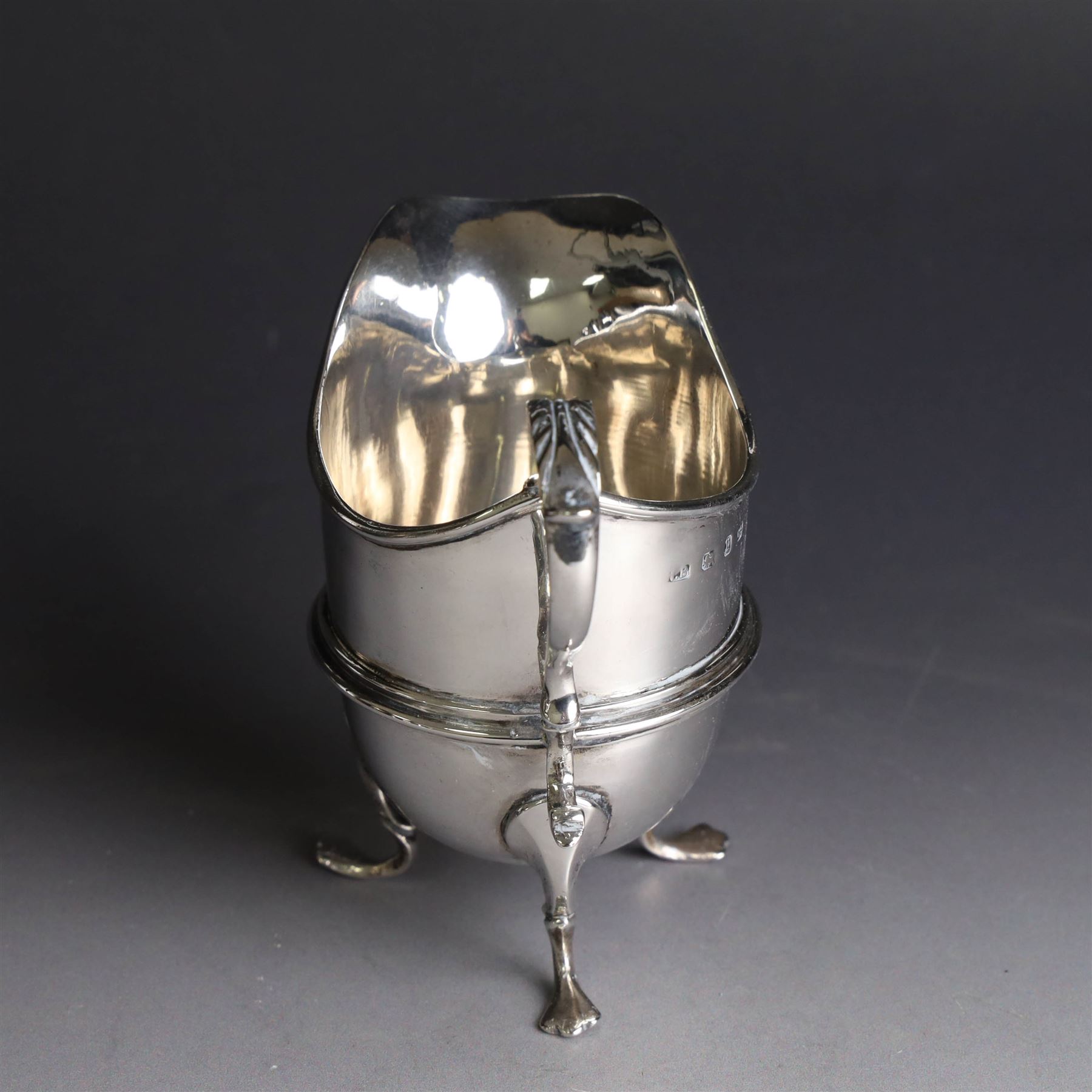 Late Victorian silver helmet shaped cream jug, with acanthus capped handle and upon three pad feet, hallmarked Birmingham 1898, maker's mark worn and indistinct, probably T Beardsmore, H10cm