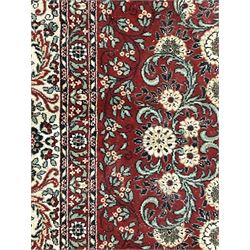 Persian design crimson ground carpet, the central rosette medallion surrounded by scrolling leaves and flower heads, the spandrels decorated with floral design and scrolling foliage, repeating border within guard stripes