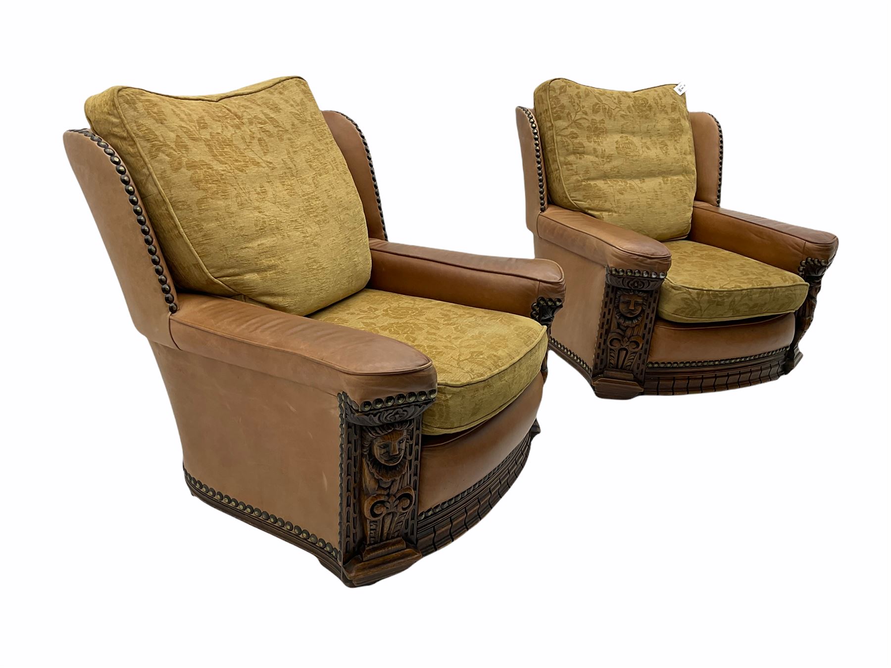 Pair of 1930’s carved oak framed club chairs, upholstered in tan studded leather with beige fabric loose cushions