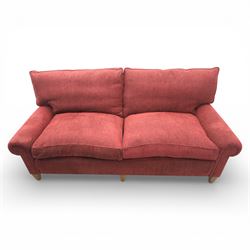 Late 20th century three seat sofa upholstered in red fabric, with gently rounded scroll arms, loose seat and back cushions, raised on tapered wooden legs