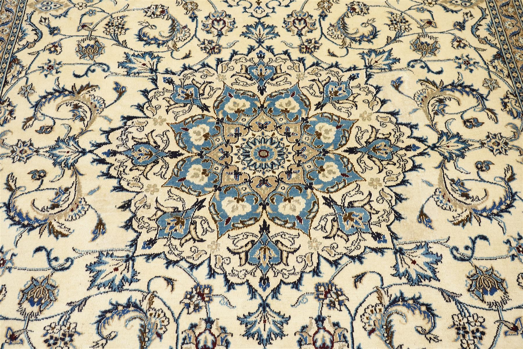 Central Persian Nain hand-knotted carpet, ivory field with central radiating medallion, issuing an all-over design of scrolling vines, palmettes, and delicate floral sprays with conforming spandrels, enclosed by a foliate border, framed by multiple guard stripes, with cotton fringe ends 