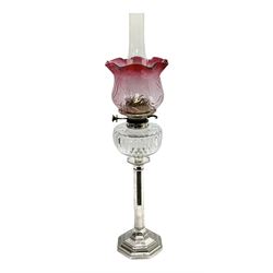 20th century Hawksworth, Eyre & Co silver plated oil lamp, the octagonal stepped base with engraved dedication, leading to an octagonal column supporting a faceted clear glass reservoir, Hinks Duplex burner, clear glass chimney, and cranberry glass shade, overall H71.5cm