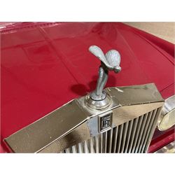 Early 1980s Rolls-Royce Corniche 'pedal' car by Sharna Tri-ang Limited, registration no.RRM1, steel chassis with treadle pedals, red moulded plastic body with flexible plastic 'Spirit of Ecstasy' car mascot on the radiator cap, opening boot lid, dashboard with decals of faux wood panelling and gauges, battery powered working electric lights, Sharna 235/70HR15 wheels with Rolls Royce hub caps, L123cm; together with two keys on RR fob, instructions manual in wallet, date stamped 17 November 1983, toy road tax disc dated 31.01.83/84 and original battery charger. 
Auctioneers Note: In 1983 Sharna Tri-ang Ltd., based at Lumb Mill in Droylsden, Manchester, took over from Tri-ang Toys at Merthyr Tydfil. They went on to launch a new range of toys based on children's TV programs, such as Knight Rider, Street Hawk, Roland Rat, The A-Team, The Get A-Long Gang and Postman Pat, as well as Rolls-Royce Corniche pedal cars, which were available in red, white or blue. 