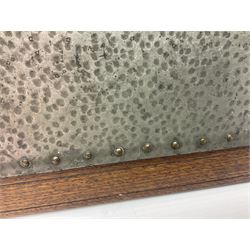 Arts and Crafts oak stand by Arthur Simpson of Kendal, of rectangular form with central hammered pewter panel, surrounded by a border with carved foliate corners, upon two bar supports, bearing label detailed 