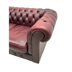 Two seat Chesterfield sofa, upholstered in buttoned oxblood leather with loose seat cushions, on bun feet